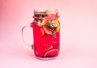 Jar of tasty cold lemonade on a pink background