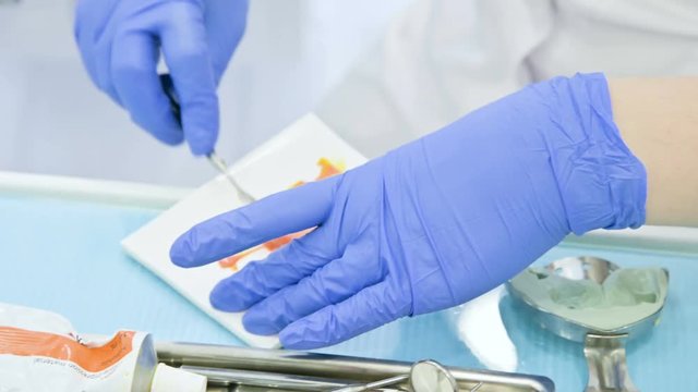 Close-up of the hand of dentistry mix components for a composite preform for removing the form from the jaw and the bite of the patient