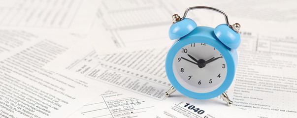 1040 Individual income tax return form and blue alarm clock