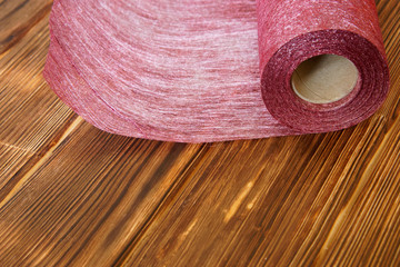 Roll of craft material from felt for home needlework on a wooden background from pine boards