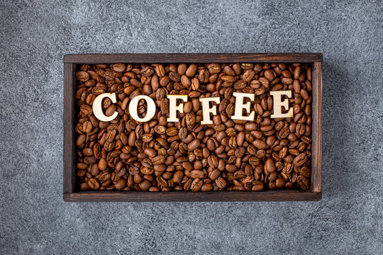 Roasted coffee beans  with text in wooden box on gray concrete background. Drink background.