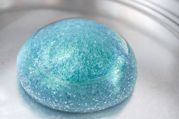 Light blue konjac sponge in water. Facial massage and exfoliating beauty accessory.
