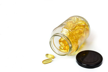 close up of gold pile fish oil capsules isolated in a glass bottle on white background. Omega 3. Vitamin E. Capsules salmon fish oil view. Supplementary food background.