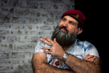  Ein Mann mit Bart, rotem Hut und Ringen aus Edelsteinen, Ketten und Accessoires