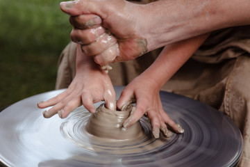 Rotating potter's wheel and clay ware on it taken from above. A sculpts his hands with a clay cup on a potter's wheel. Hands in clay.