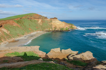 Elevated, view of a bay with eroded, red, sandstone cliffs in the Chatham islands, New Zealand.