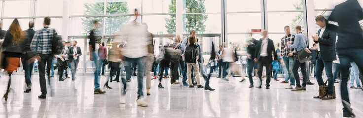 large crowd of anonymous blurred people at a trade show hall