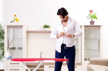 Young man ironing in the bedroom