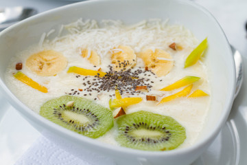 Yogurt con kiwi mango chia en plato de ceramica blanco con manteles blancos