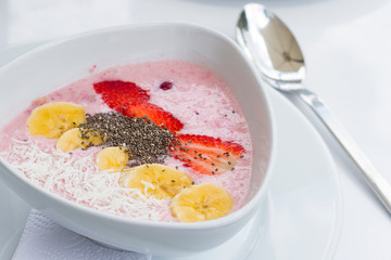 Yogurt con kiwi mango chia en plato de ceramica blanco con manteles blancos