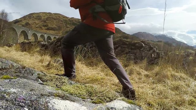 Slow-motion video of backpacker walking toward Glenfinnan viaduct in Scotland