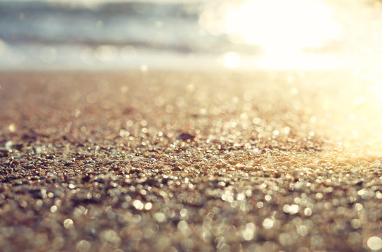 background image of sandy beach and ocean waves with bright bokeh lights
