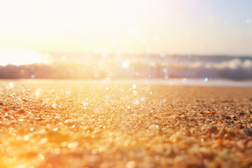 background image of sandy beach and ocean waves with bright bokeh lights