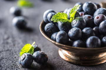 Vintage bowl full of fresh blueberries with herbs.