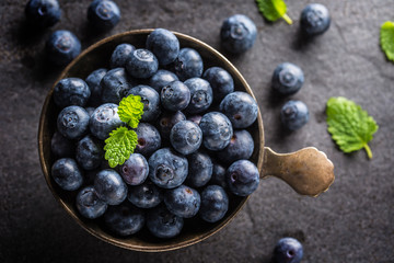 Vintage bowl full of fresh blueberries with herbs.