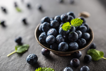 Vintage bowl full of fresh blueberries with herbs.