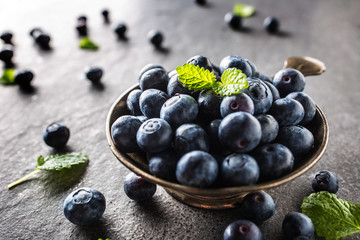 Vintage bowl full of fresh blueberries with herbs.