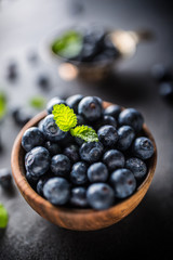 Wooden bowl full of fresh blueberries with herbs