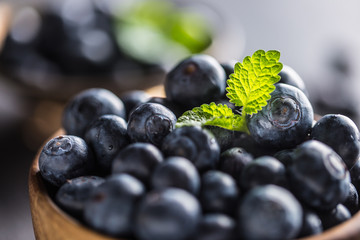 Wooden bowl full of fresh blueberries with herbs