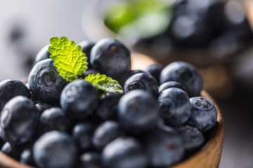 Wooden bowl full of fresh blueberries with herbs