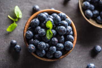Wooden bowl full of fresh blueberries with herbs