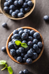 Wooden bowl full of fresh blueberries with herbs