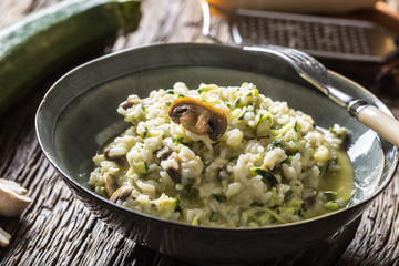 Italian risotto zucchini mushrooms and parmesan in dark plate
