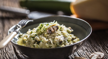 Italian risotto zucchini mushrooms and parmesan in dark plate