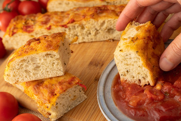 Italian Bread Focaccia With Tomatoes and Bruschetta Tomato Sauce on a Kitchen Table close Up, Woman Hand
