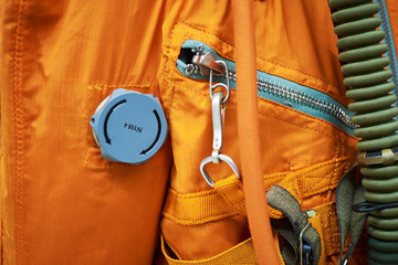Part of orange astronaut uniform, closeup. Cosmonaut protective suit