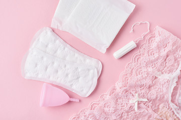 Sanitary pad, menstrual cup, tampon and panties on a pink background
