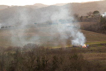 Fototapeta na wymiar Fire burning on a brown farmland in Tuscany, Italy