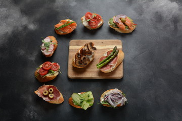 Brushetta or traditional Spanish-tapas. Appetizers with Italian antipasti snacks. Variety of small sandwiches with prosciutto,cherry tomatoes, salmon, cream cheese, cucumber, radish, asparagus