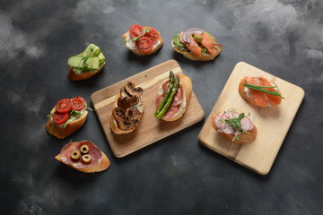 Brushetta or traditional Spanish-tapas. Appetizers with Italian antipasti snacks. Variety of small sandwiches with prosciutto,cherry tomatoes, salmon, cream cheese, cucumber, radish, asparagus