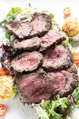 sliced beef steak over a salad