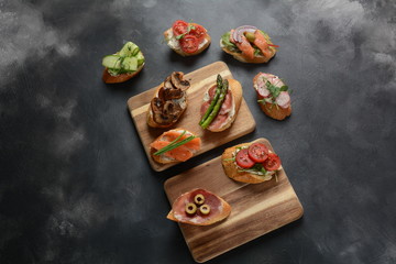 Brushetta or traditional Spanish-tapas. Appetizers with Italian antipasti snacks. Variety of small sandwiches with prosciutto,cherry tomatoes, salmon, cream cheese, cucumber, radish, asparagus