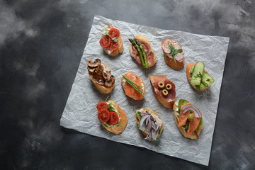 Brushetta or traditional Spanish-tapas. Appetizers with Italian antipasti snacks. Variety of small sandwiches with prosciutto,cherry tomatoes, salmon, cream cheese, cucumber, radish, asparagus