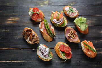 Brushetta or traditional Spanish-tapas. Appetizers with Italian antipasti snacks. Variety of small sandwiches with prosciutto,cherry tomatoes, salmon, cream cheese, cucumber, radish, asparagus