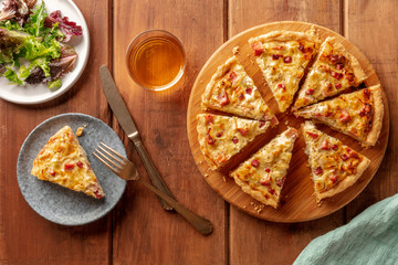 French dinner. A quiche with wine and mesclun salad leaves, shot from above on a dark rustic wooden background