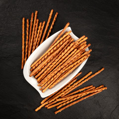 An overhead photo of salty sticks, shot from the top on a black background with copy space. Party snacks with a place for text