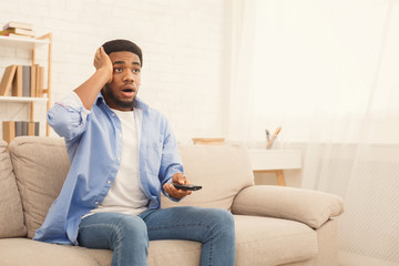 African-american man watching tv at home, copy space