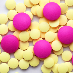 Fototapeta na wymiar Yellow and pink pills on a white background.