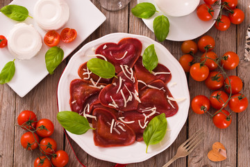 Red heart ravioli with tomato, mozzarella and basil.