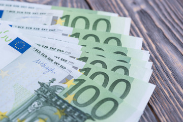 Euro cash banknotes on a dark wooden background.