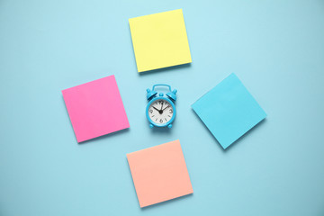 Blue alarm clock and a reminder note. Time management concept. Copy space for text.