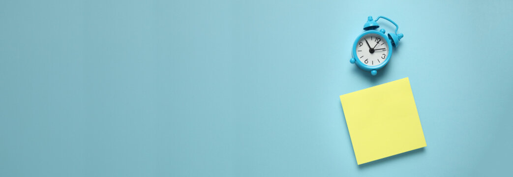 Blue alarm clock and a reminder note. Time management concept. Copy space for text.