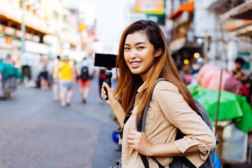 Young Asian female tourist woman holding a gimbal with smartphone and recording videos for blog....