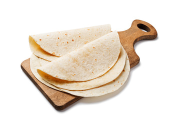 Homemade wheat flour tortilla on wooden cutting board isolated on white background.