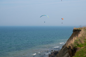 Fototapeta na wymiar some paragliders fly along the steep coast of the Baltic Sea