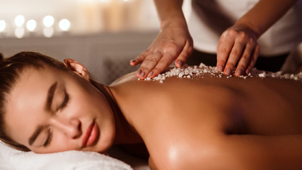 Woman enjoying salt scrub massage at spa